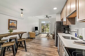 A modern kitchen with wooden cabinets, a dining area with a table and chairs, a ceiling fan, and a view through a glass door. - Riverfront Condo Only 10 Minutes to the Resort! Pet Friendly. (Steamboat Springs)