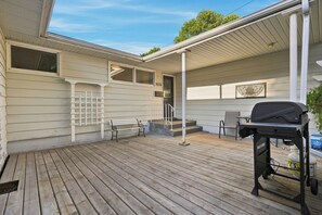 Eine überdachte Terrasse im Freien mit Grill, Bank und kleinem Tisch.