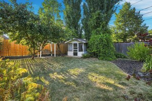Ein Garten mit Holzzaun, einer kleinen Gartenhütte und Rasen.