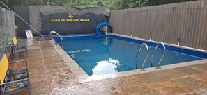 Una piscina amb un senyal de prohibició de circular, envoltada d'una zona tancada amb un cartell que diu 'FARM DE MUKUND SADAN'.