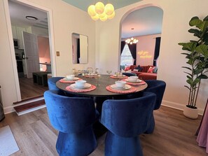 A dining area with a round table set for four, surrounded by blue upholstered chairs. - The Slide House - Theater - Hot Tub - Sleep 12 (Charlotte)