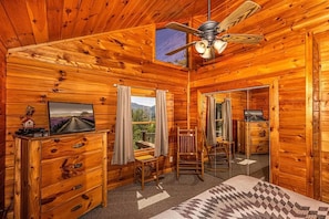 A log cabin interior with a bed, wooden dresser, and a ceiling fan. - Shooting Star Ridge ~ Secluded Mountain Cabin w/ Hot Tub & Fireplace (Whittier)