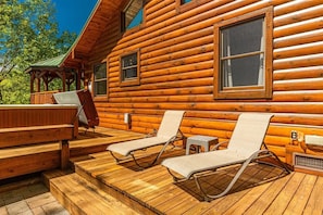 A wooden cabin with a deck, two lounge chairs, a hot tub, and a covered area. - Shooting Star Ridge ~ Secluded Mountain Cabin w/ Hot Tub & Fireplace (Whittier)