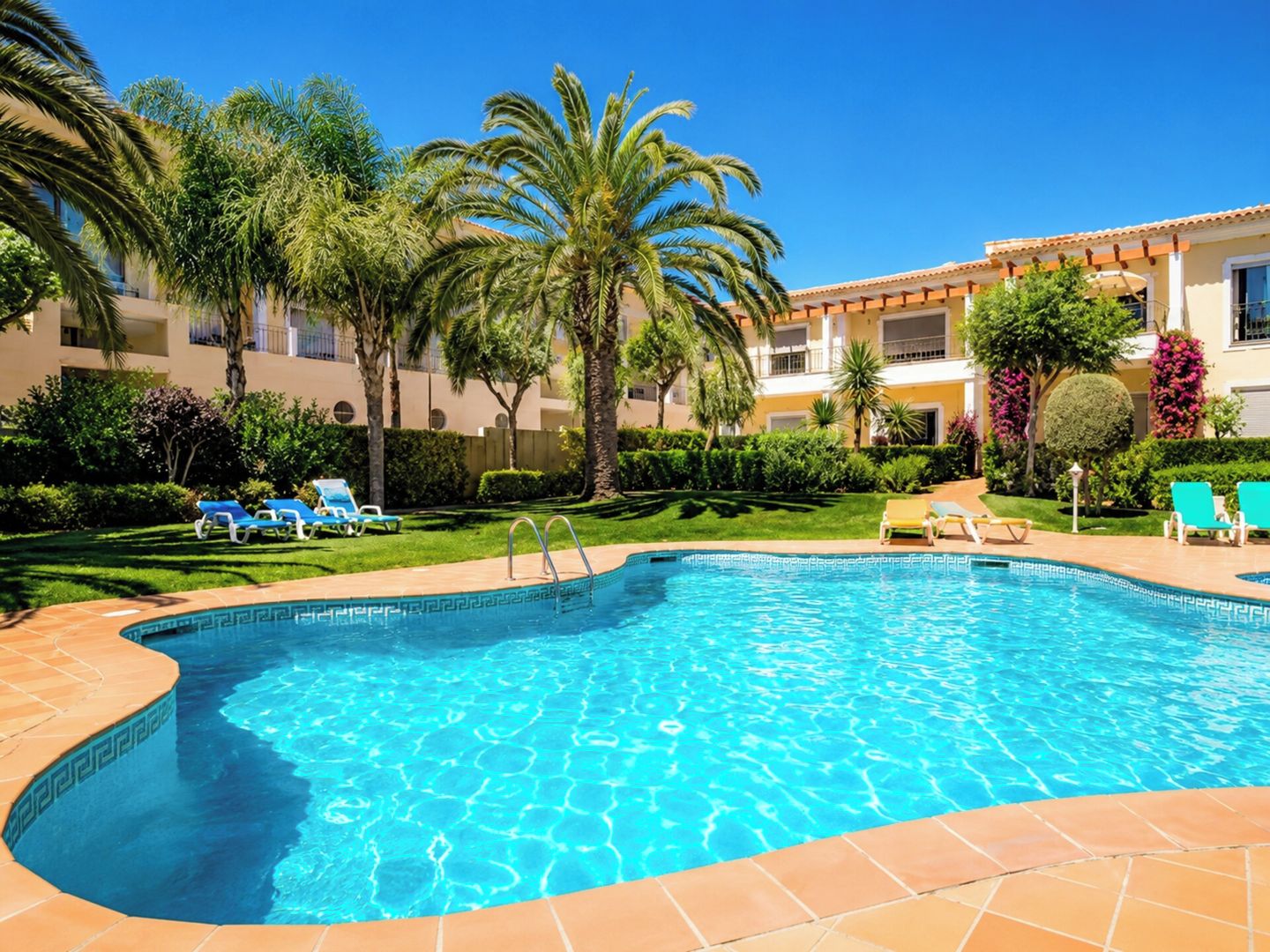 A swimming pool with a clear blue water surface, surrounded by a tiled deck.