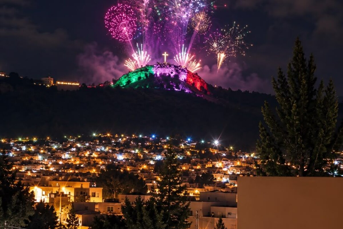 A nighttime view of a town with a hill in the background.