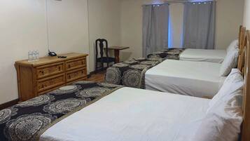 A hotel room with two beds, a wooden dresser, a flat-screen TV, and a table.