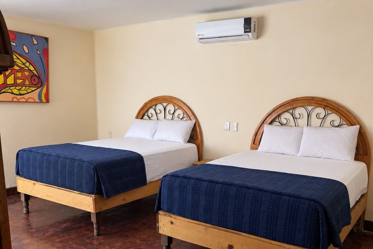 Two wooden beds with headboards, a wall-mounted air conditioner, and a wooden floor.