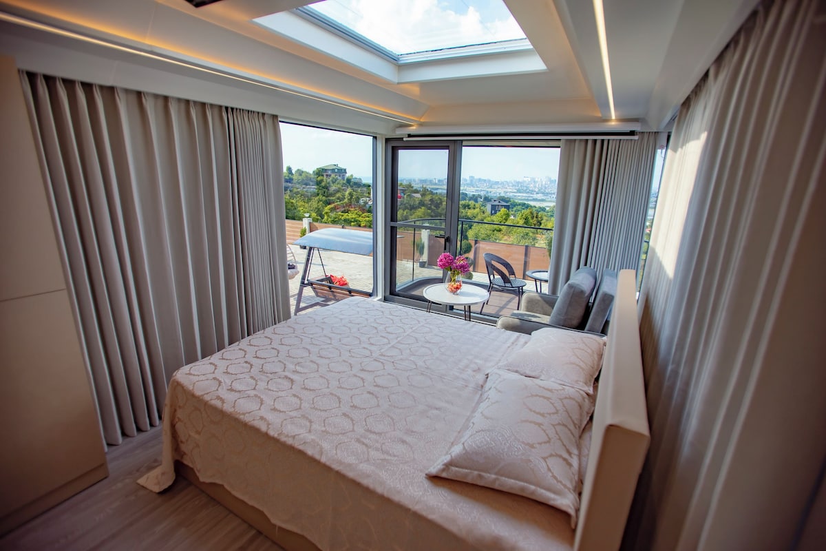 Un dormitorio con una cama grande, un tragaluz y vistas a un paisaje urbano.