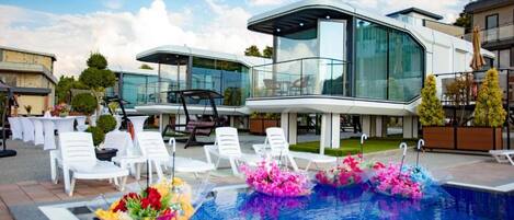 A modern outdoor pool area with lounge chairs and a glass-enclosed structure.