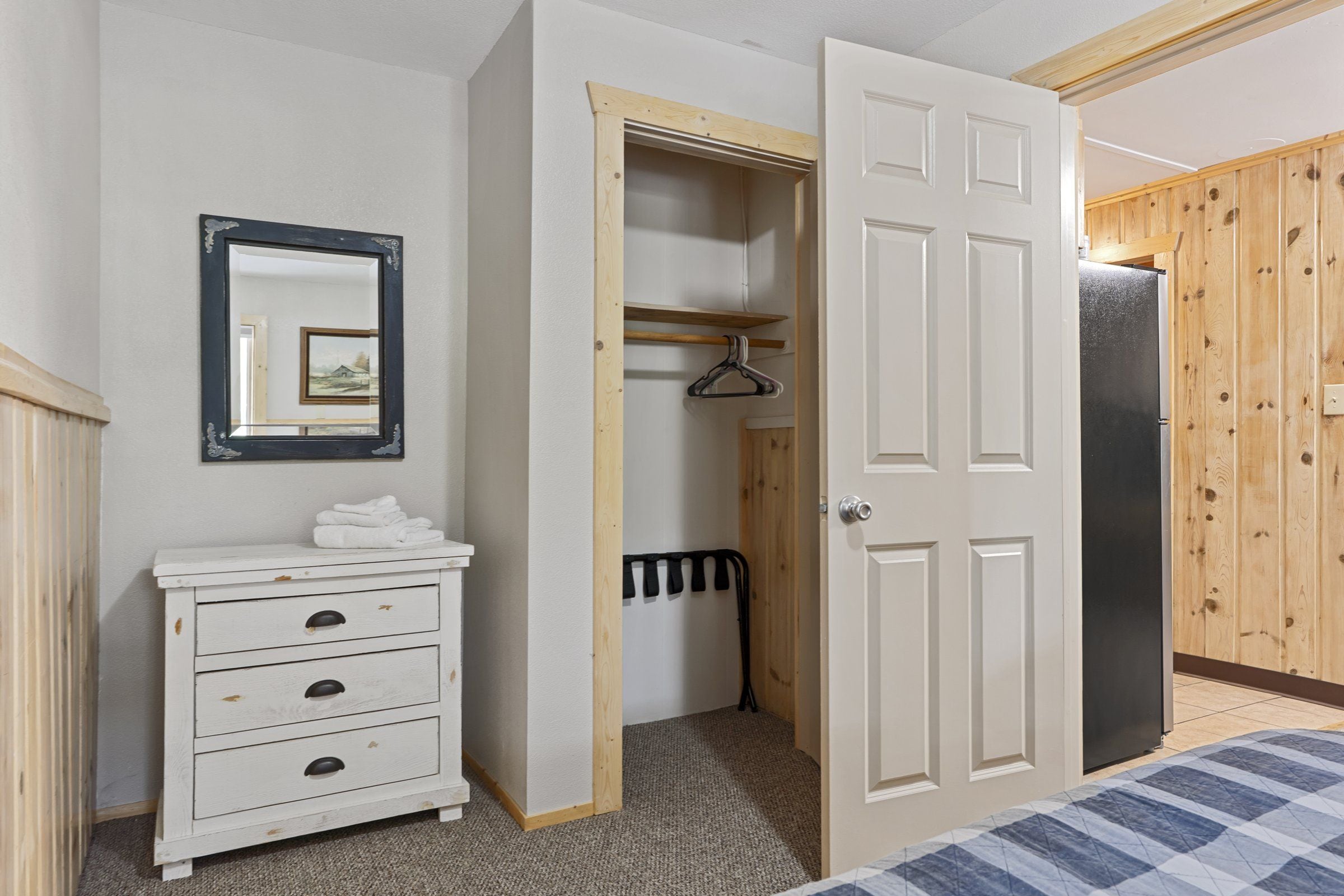 A bedroom with a bed, a dresser, a mirror, a wardrobe, and a radiator.