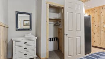 A bedroom with a bed, a dresser, a mirror, a wardrobe, and a radiator.