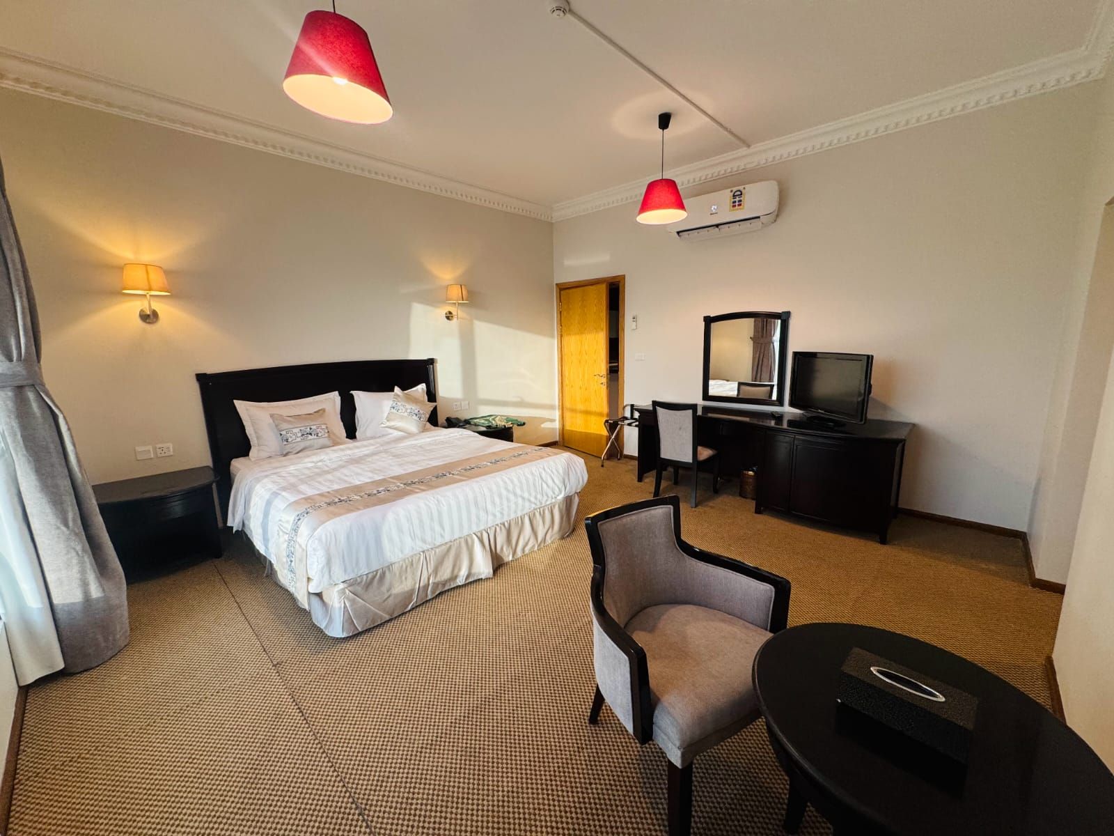 Ein Hotelzimmer mit einem Bett, einem Schreibtisch mit Stuhl, einem Fernseher und zwei Pendelleuchten.