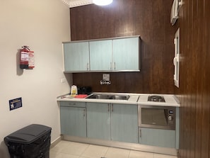 A kitchen with light blue cabinets, a stainless steel sink, and a built-in microwave. - Al Jawhara Suite Serviced Apartments 2 (Taif)