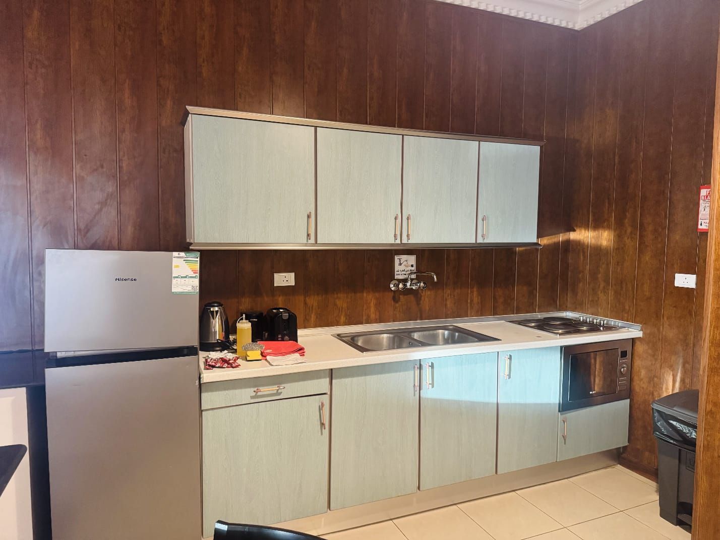 Eine kleine Küche mit Kühlschrank, Spüle, Herd und Holzschränken.