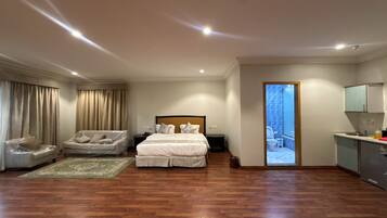 Un dormitorio amplio con una cama grande, un área de descanso y vistas al exterior.