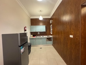A compact kitchen with a refrigerator, a sink, and a microwave.