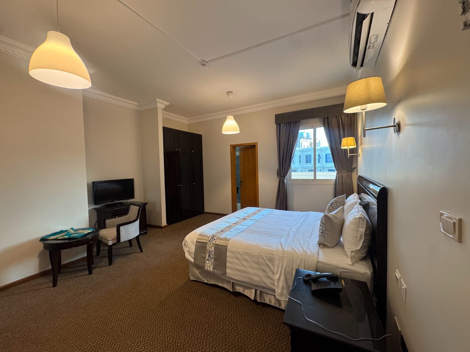 Une chambre d’hôtel avec un lit, un bureau, une télévision et une fenêtre avec des rideaux.