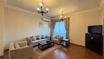 A living room with a sofa, armchair, coffee table, and TV stand.