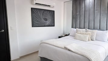 A modern bedroom with a bed, a wall-mounted air conditioner, a framed abstract artwork, and a grey headboard.