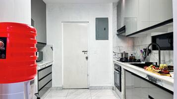 Una cucina moderna con mobili bianchi, un piano di lavoro in marmo e un erogatore d'acqua rosso.