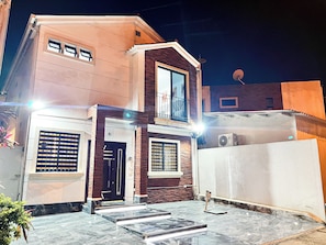 A two-story building with a balcony, a satellite dish, and a sign indicating a no parking zone.