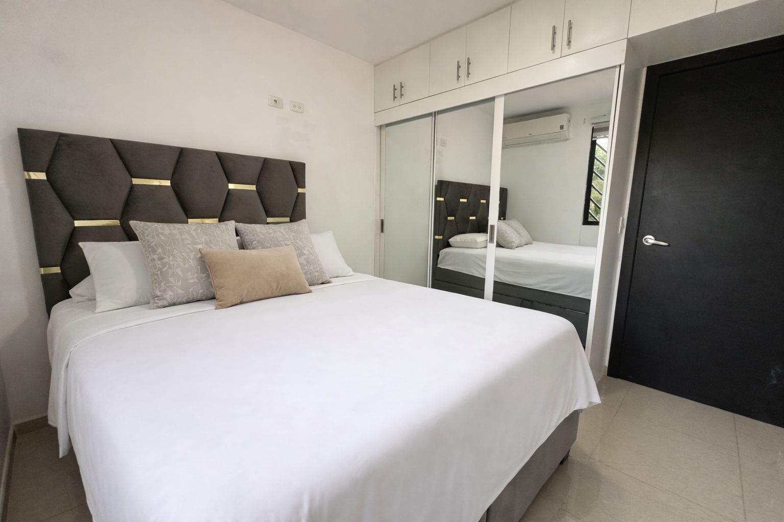 A modern bedroom with a large bed, a wardrobe, and a door.