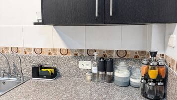 A kitchen with a granite countertop, a black cabinet above, and a patterned backsplash.