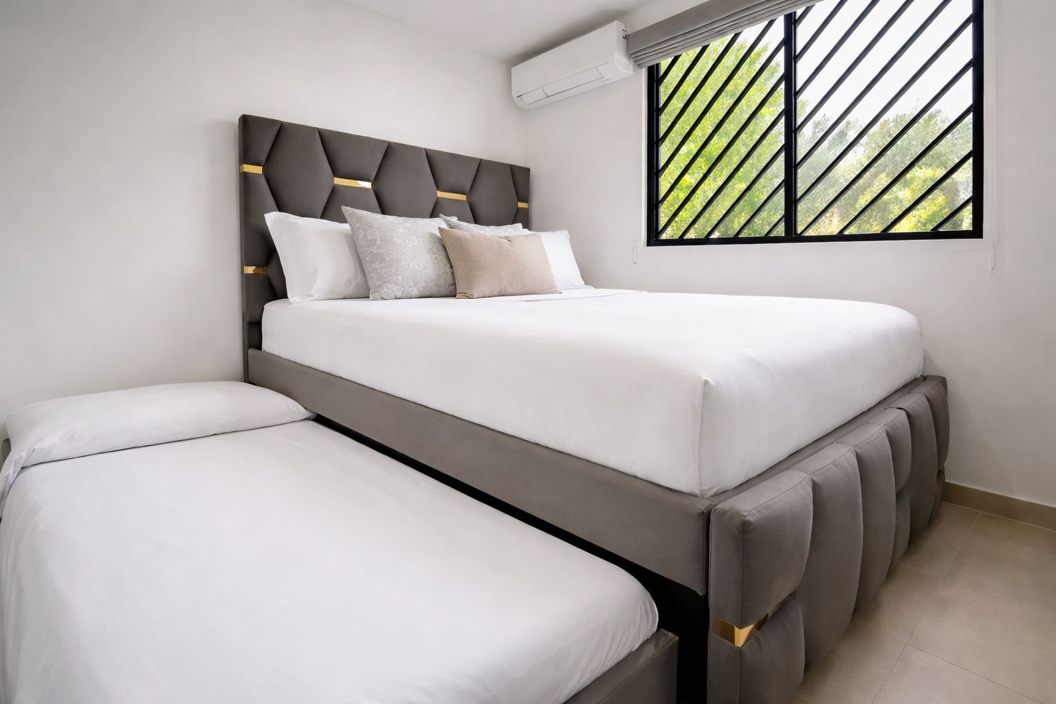 A modern bedroom with a bed, a bench, and a window with a view of trees.