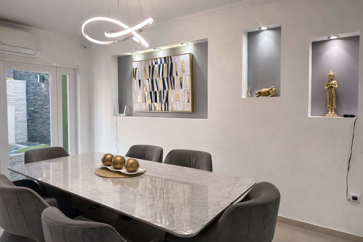 A modern conference room with a marble table, grey chairs, and decorative wall art.
