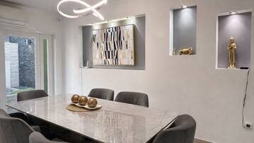 A modern conference room with a marble table, grey chairs, and decorative wall art.