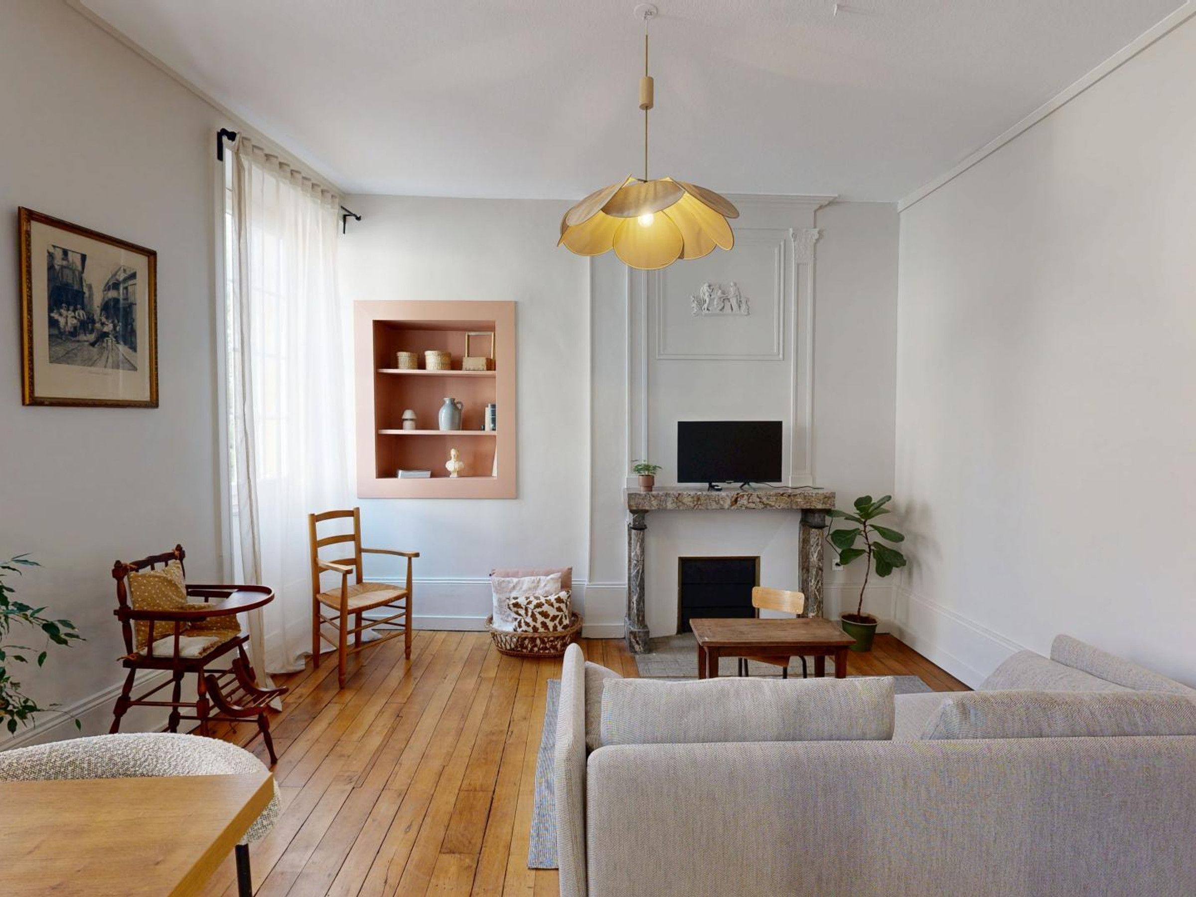 Een woonkamer met een open haard, een bank, een houten tafel en een stoel.