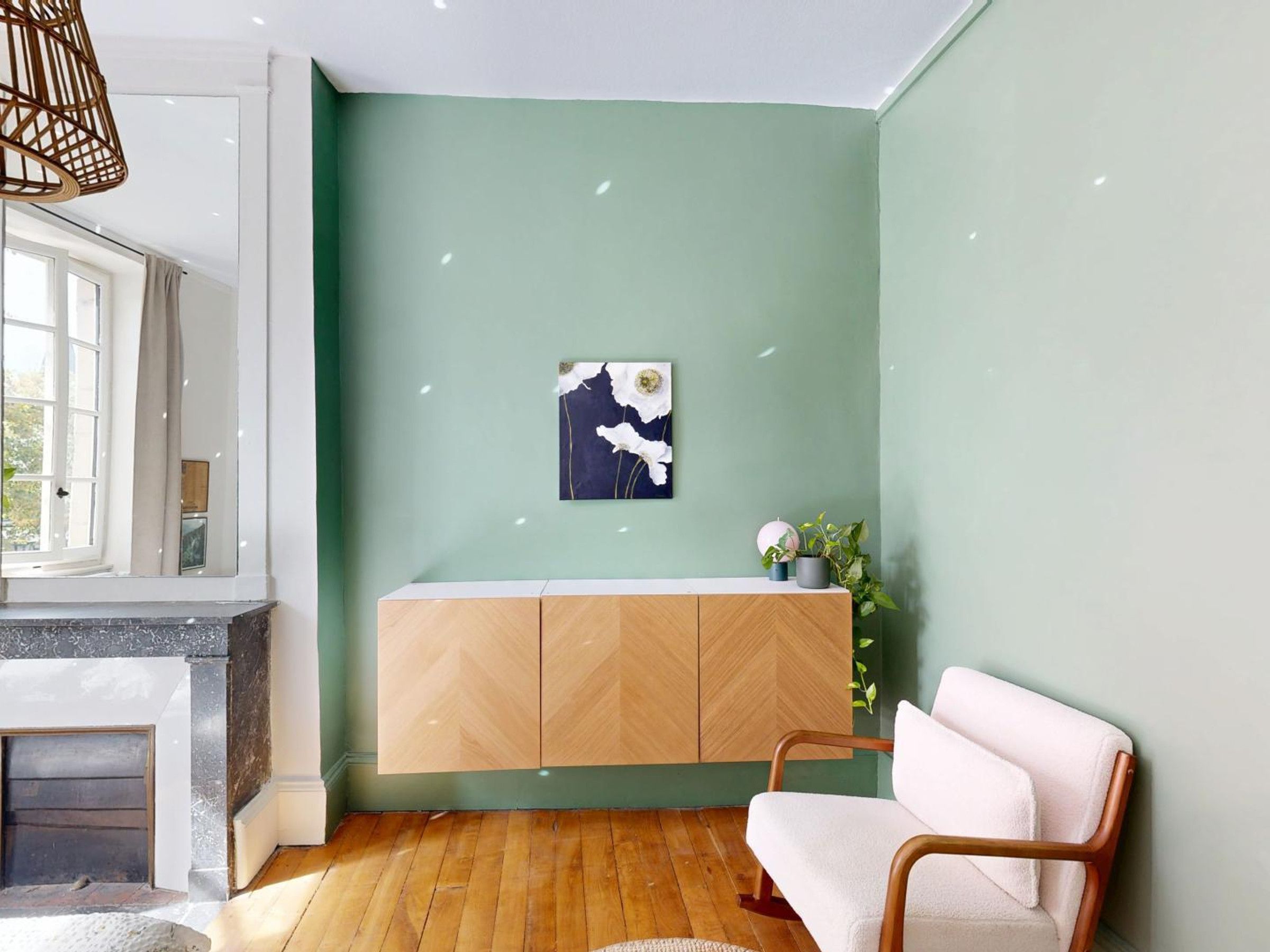 Een kamer met een groene wand, een witte bank, een houten kast en een open haard.