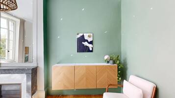 Een kamer met een groene wand, een witte bank, een houten kast en een open haard.