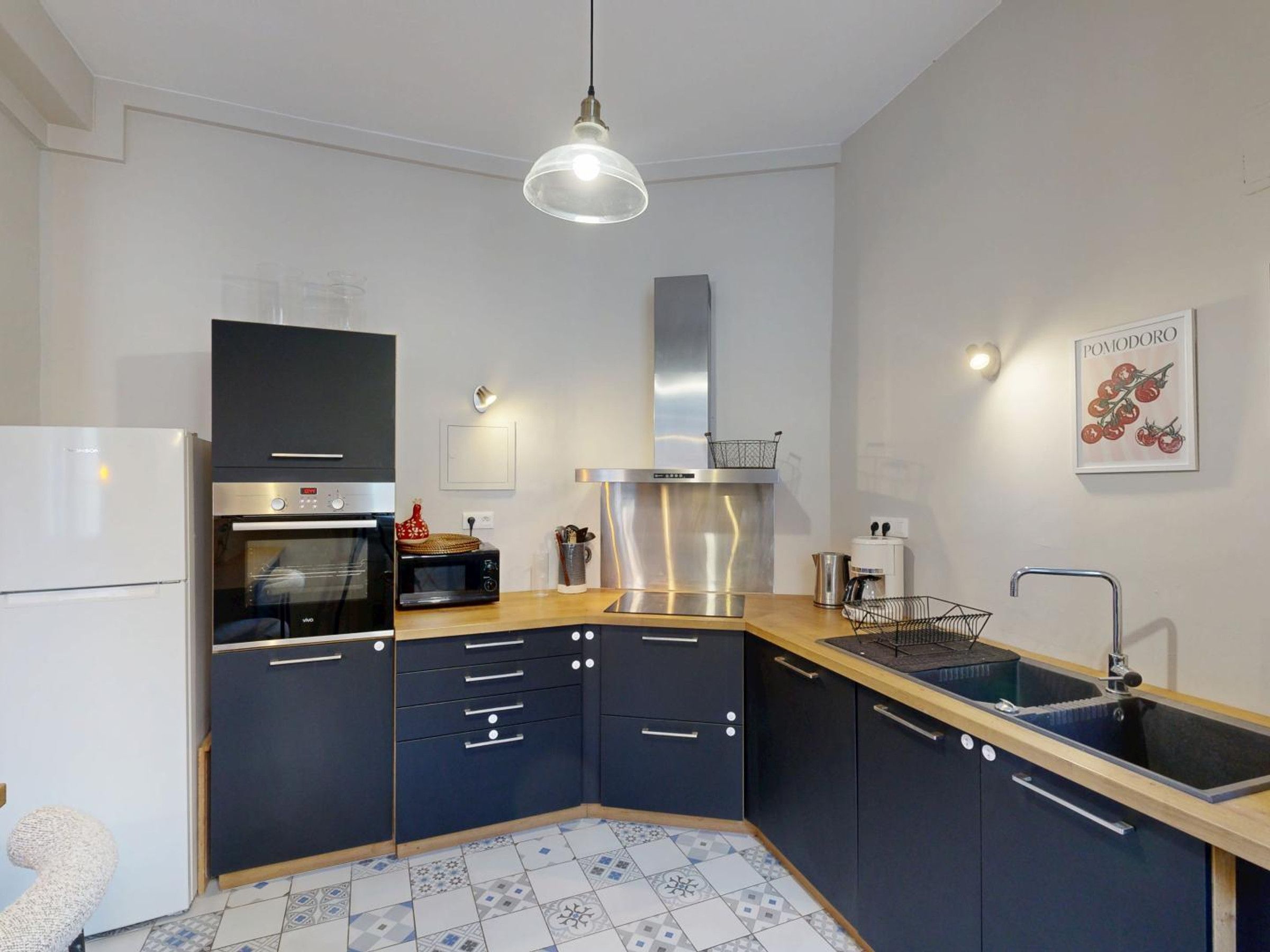 Eine moderne Küche mit eingebautem Backofen, Mikrowelle und einer Edelstahl-Dunstabzugshaube.