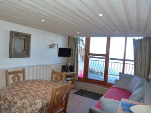 Ein Zimmer mit Bett, Sofa, Fernseher und einem Balkon mit Blick.