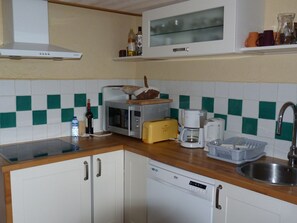Eine kleine Küche mit Mikrowelle, Toaster, Kaffeemaschine und Geschirrspüler.
