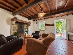 Ein rustikales Interieur mit Kamin aus Stein, Ledermöbeln und Holzbalkendecke.