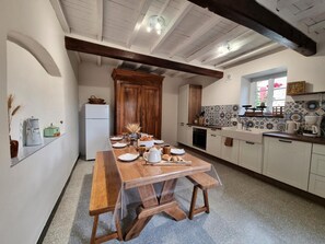 A kitchen with a wooden table, white cabinets, and a tiled backsplash. - Spacious house, pets allowed, panoramic view - 12 guests (Saint-Alban-les-Eaux)