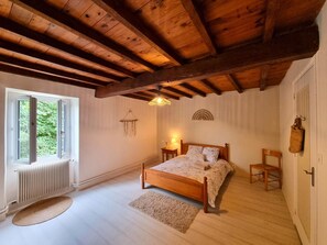 A bedroom with a wooden ceiling, a bed with a headboard, a window, a radiator, and a wall-mounted lamp. - Spacious house, pets allowed, panoramic view - 12 guests (Saint-Alban-les-Eaux)