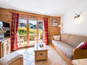 Ein gemütliches Wohnzimmer mit einer Couch, einem Couchtisch und einem Fernseher an einer Holzwand.