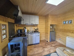 Eine kleine Küche mit Holzwänden, einem Kühlschrank und einem Waschbecken.