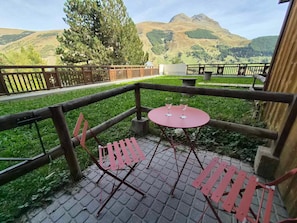 Eine Terrasse mit Tisch und Stühlen, Blick auf Berge und ein Holzzaun.