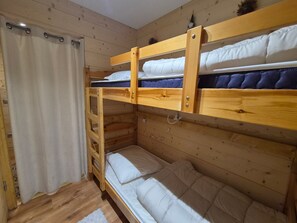 Ein Schlafraum mit Etagenbetten, Holzwänden und einer Vorhang.