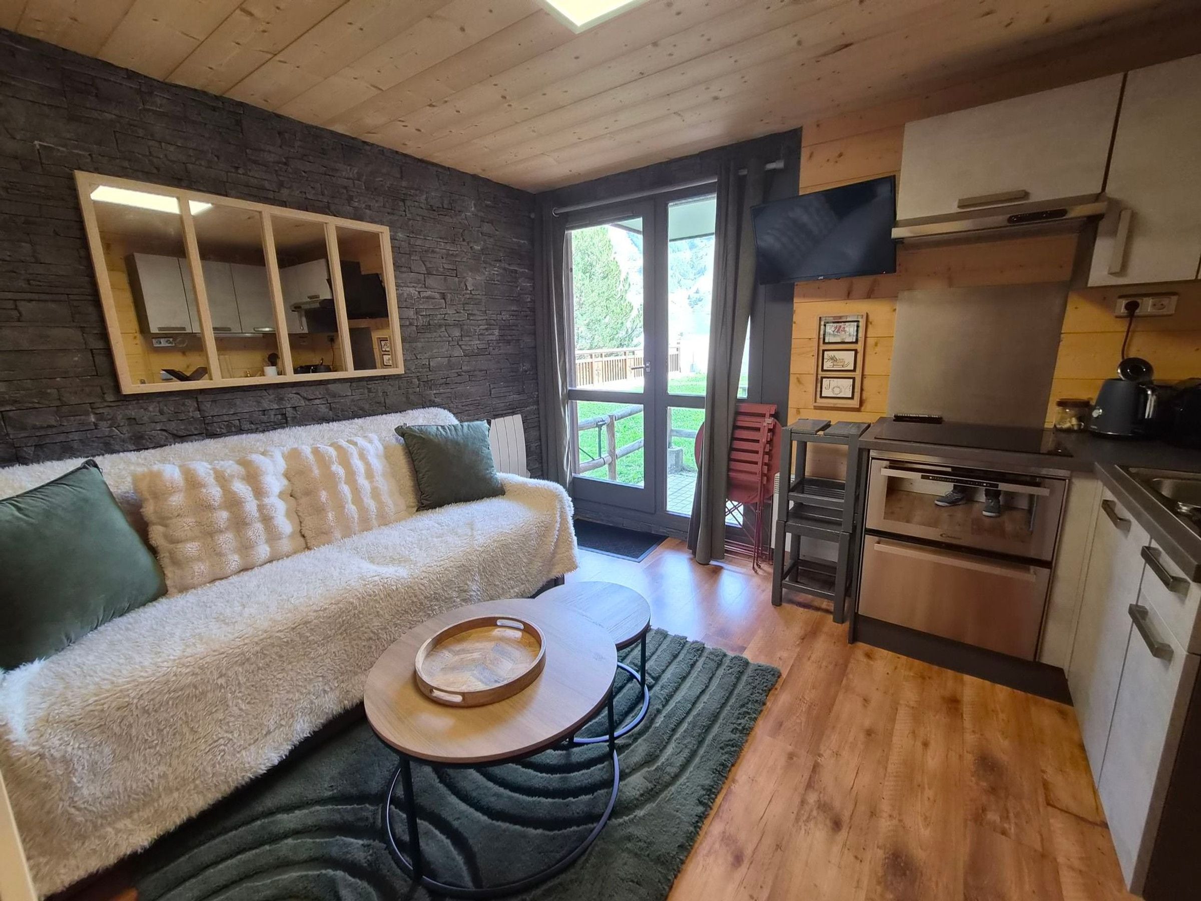 A cozy living area with a sofa, a small round table, and a kitchen with a stove and cabinets.