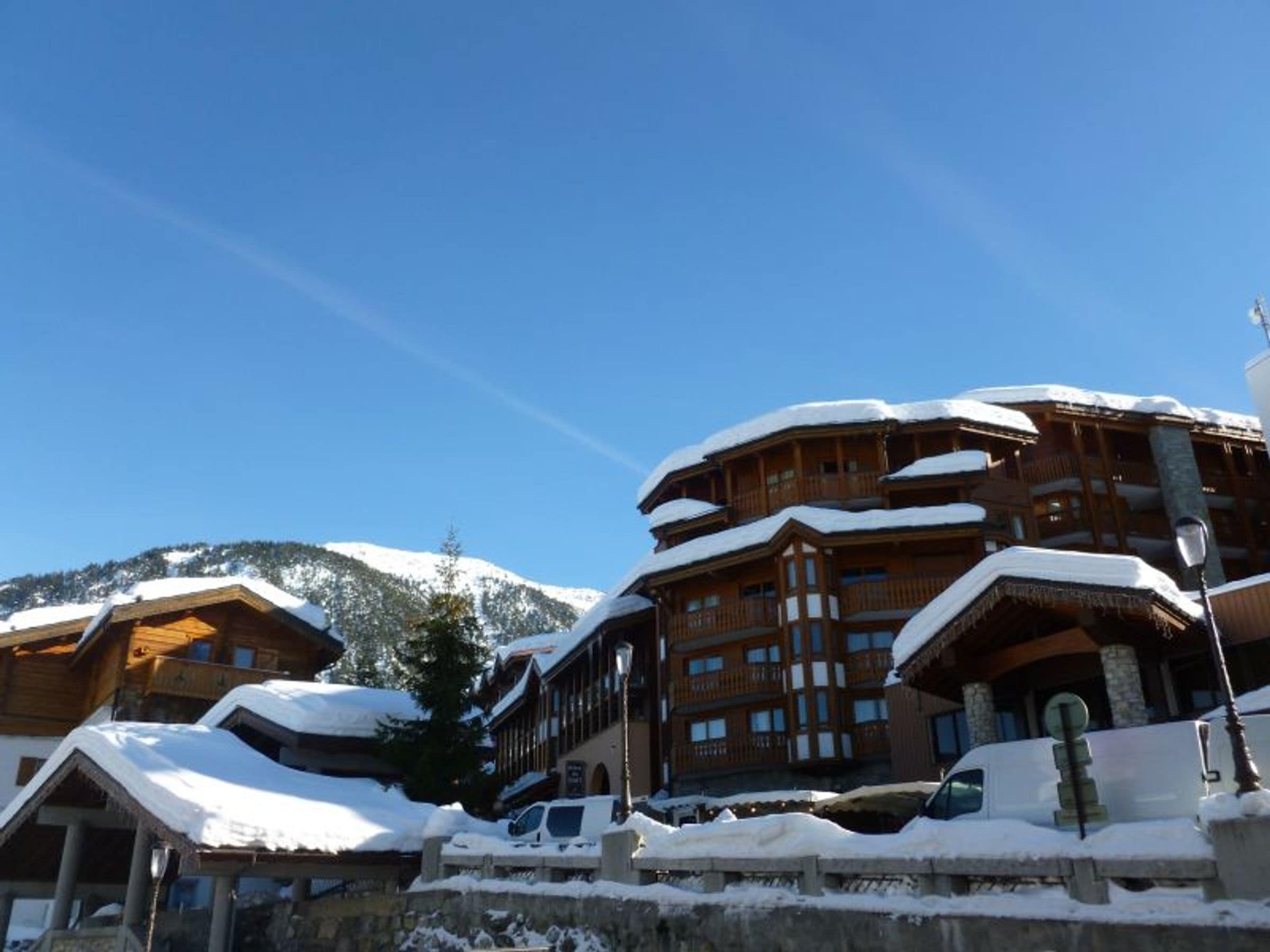 A multi-story wooden building with balconies, surrounded by snow-covered mountains.
