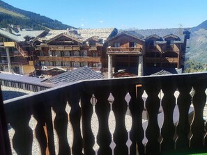 Ein Chalet-ähnliches Holzhaus mit mehreren Balkonen und einer Bergkulisse.