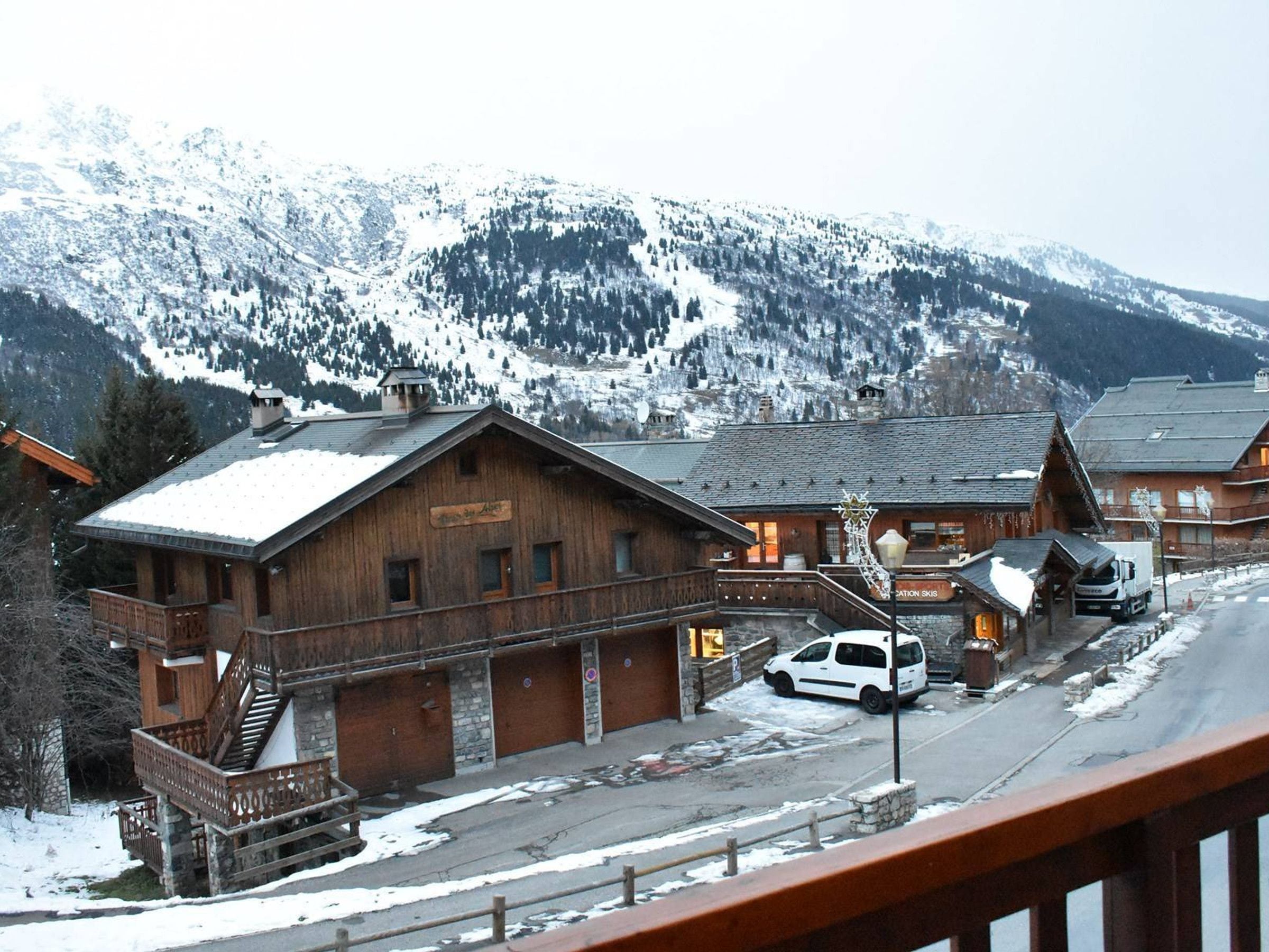 A wooden building with a sign that reads 'Hotel Alpenblick' and a car parked in front.