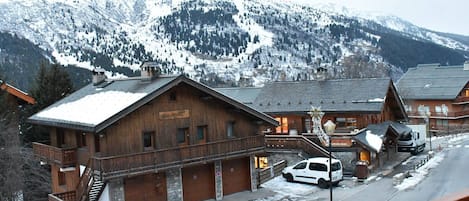A wooden building with a sign that reads 'Hotel Alpenblick' and a car parked in front.