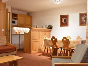 A compact living space with a kitchenette, a dining area with wooden chairs, and a sofa. - Cozy apartment mountain view - 5 guests (Méribel)