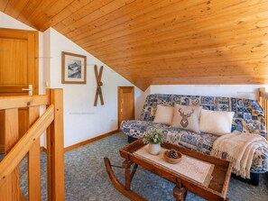 A cozy room with a wooden ceiling, a patterned sofa, a rocking chair, and a framed picture on the wall. - Spacious apartment, slopes view - 6 guests (Le Grand-Bornand)